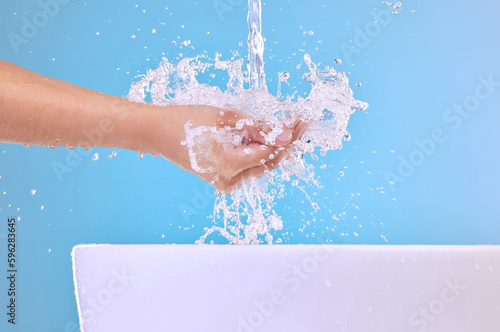 Take one to the face. Shot of an unrecognizable woman washing her hands against a blue background.