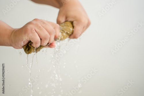 Obraz na plátně Man's hands squeeze wet fabric, outdoor drop water, short squeeze