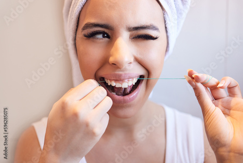 Almost got it. Shot of a beautiful young woman cleaning her teeth at home.