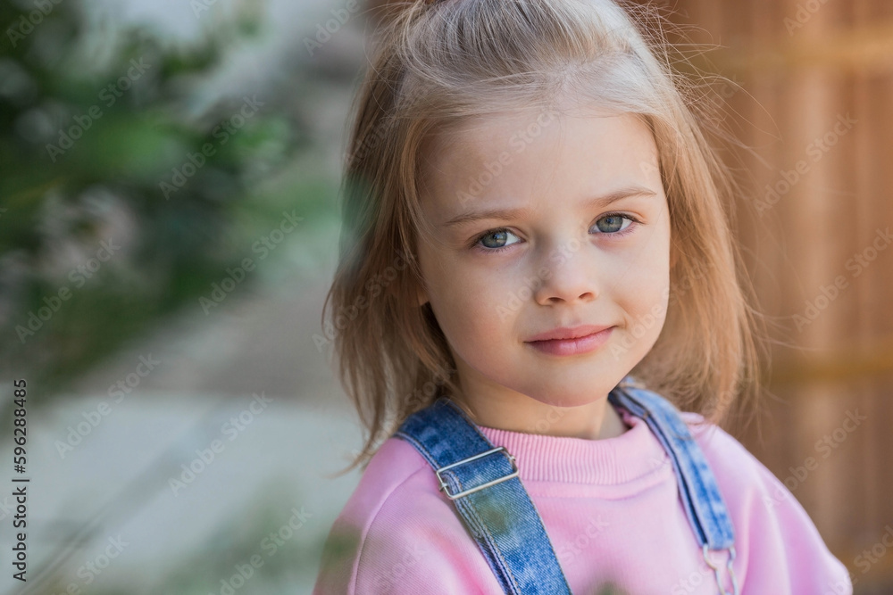 Rubs a beautiful cute girl in pink clothes with a bow on her head. The child smiles at the camera. Childhood. Rubs a beautiful cute girl in pink clothes with a bow on her head. The child smiles at the camera. Childhood.