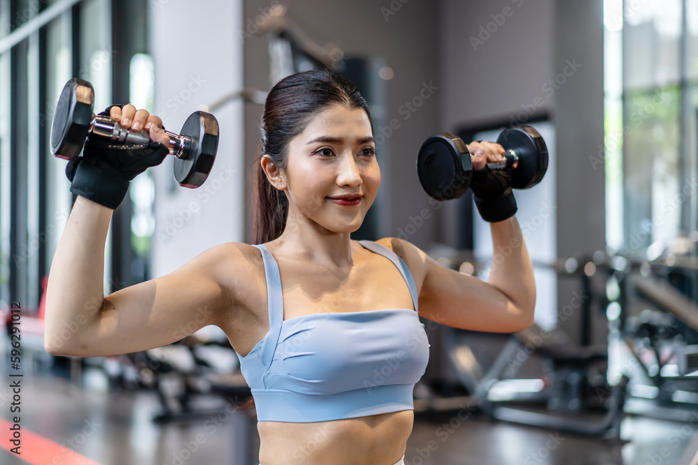 Weights training, Young asian woman lifting weights with equipment in the background, Sportswear girl workout with strong beautiful fit body shape, Asia lifestyle with copy space Weights training, Young asian woman lifting weights with equipment in the background, Sportswear girl workout with strong beautiful fit body shape, Asia lifestyle with copy space