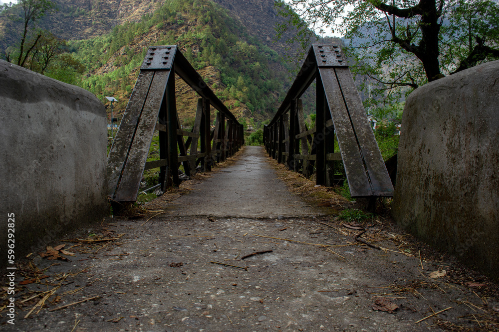 A village iron bridge way to mountains with lots of green trees