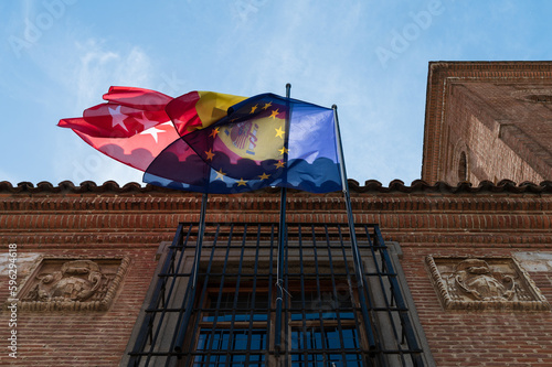 Las banderas de la comunidad de Madrid, España y Europa ondean en un edificio de Alcalá de Henares, Madrid.