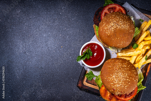 Healthy veggie burgers with vegetable cutlets. Homemade beetroot and carrot burgers, with fresh vegetables, vegan mayo tomato sauce, whole grain buns, on dark background with ingredients, copy space