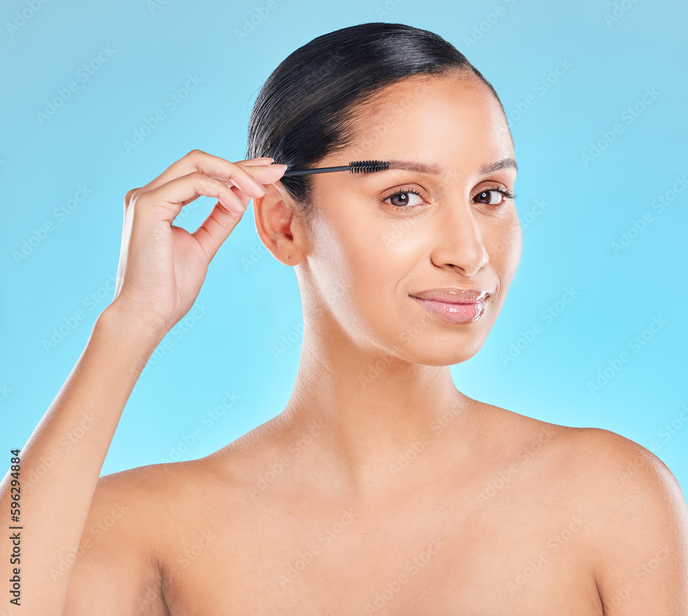 Never neglect your eyebrows. Studio portrait of an attractive young woman applying eyebrow shadow against a blue background.