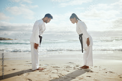 First we bow, then we fight. Full length shot of two young martial artists practicing karate on the beach.