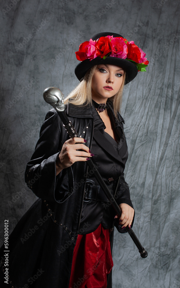 A pretentious Gothic lady in a long leather coat and a hat with roses, uses a cane.