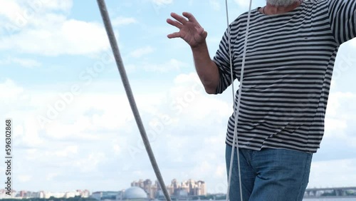 Mature Handsome sailor senior bearded man dressed in sailors shirt navy striped uniform, tells maritime stories, navigating sail boat or yacht floating in sea, sailing, age, tourism, travel and people photo