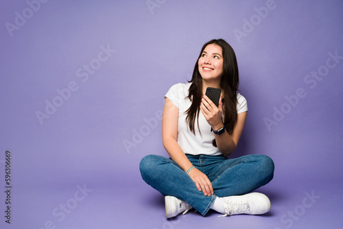 Attractive woman texting on the smartphone against a purple background
