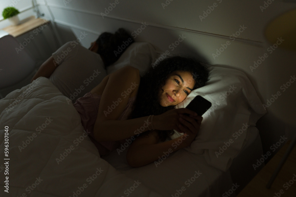 Obraz premium Excited woman texting before falling asleep