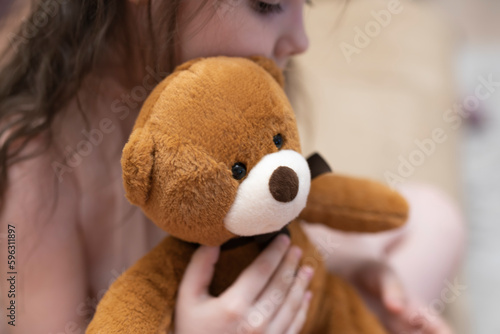 A girl, a brunette of seven years with a teddy bear in her hands. photo