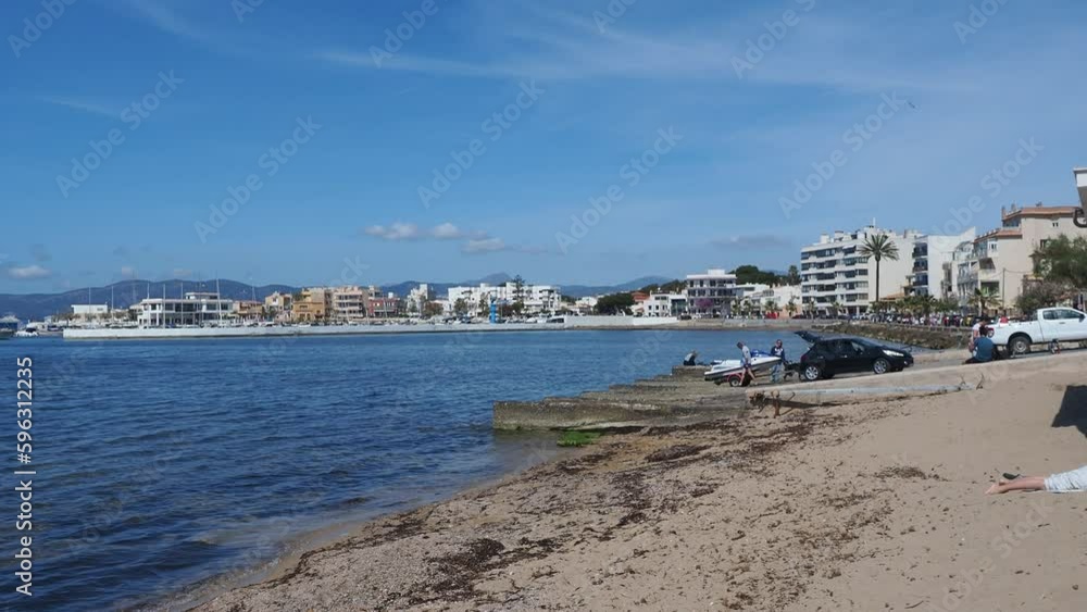 view of the town of Cala Gamba, its marina and its beach with people getting off the trailer their jet ski view of the town of Cala Gamba, its marina and its beach with people getting off the trailer their jet ski