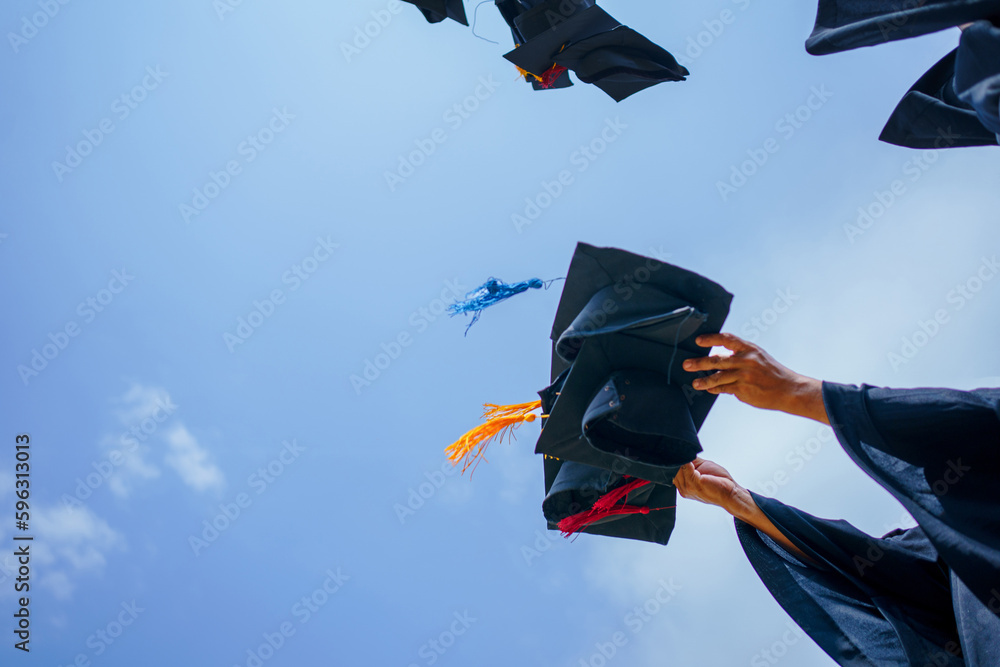 Close-up of graduation ceremony university high school graduates throwing cap on the blue sky. - obrazy, fototapety, plakaty 
