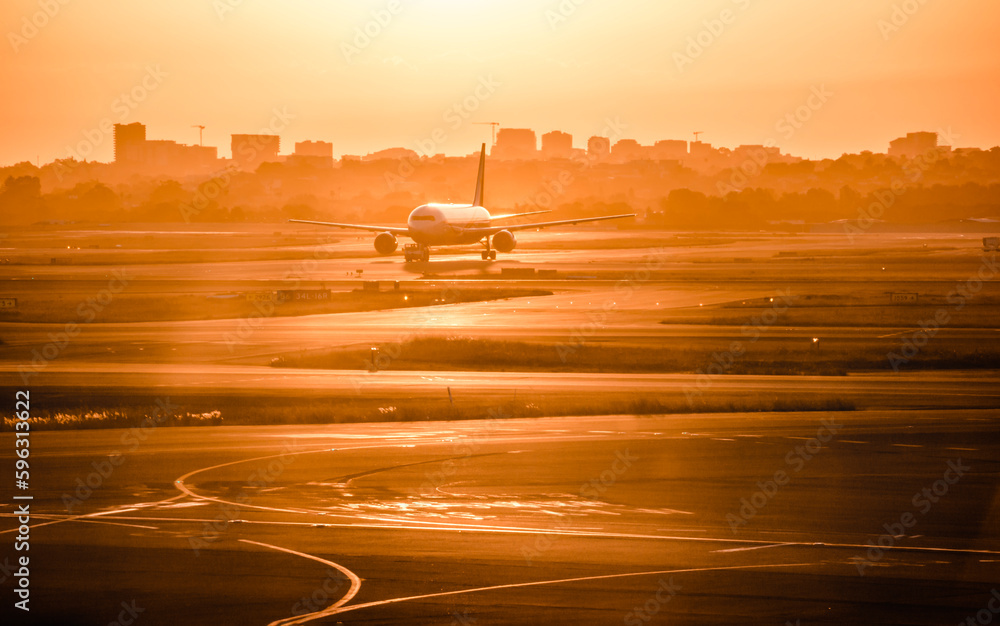 Fototapeta premium A passenger flight running on the track in Sydney airport in the sunset