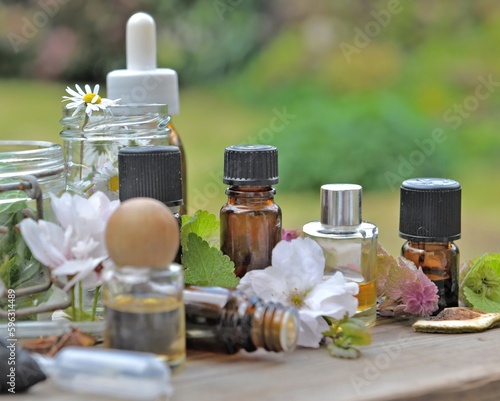 bottles of essential oil with plant and flower  on a wooden table in garden