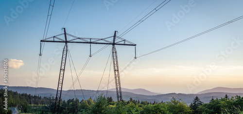 Electrical power lines and towers at at the mountain landsape. sunset.