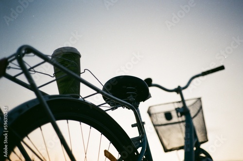 Cup of coffee stands on the trunk of a retro bike against the background of sunset