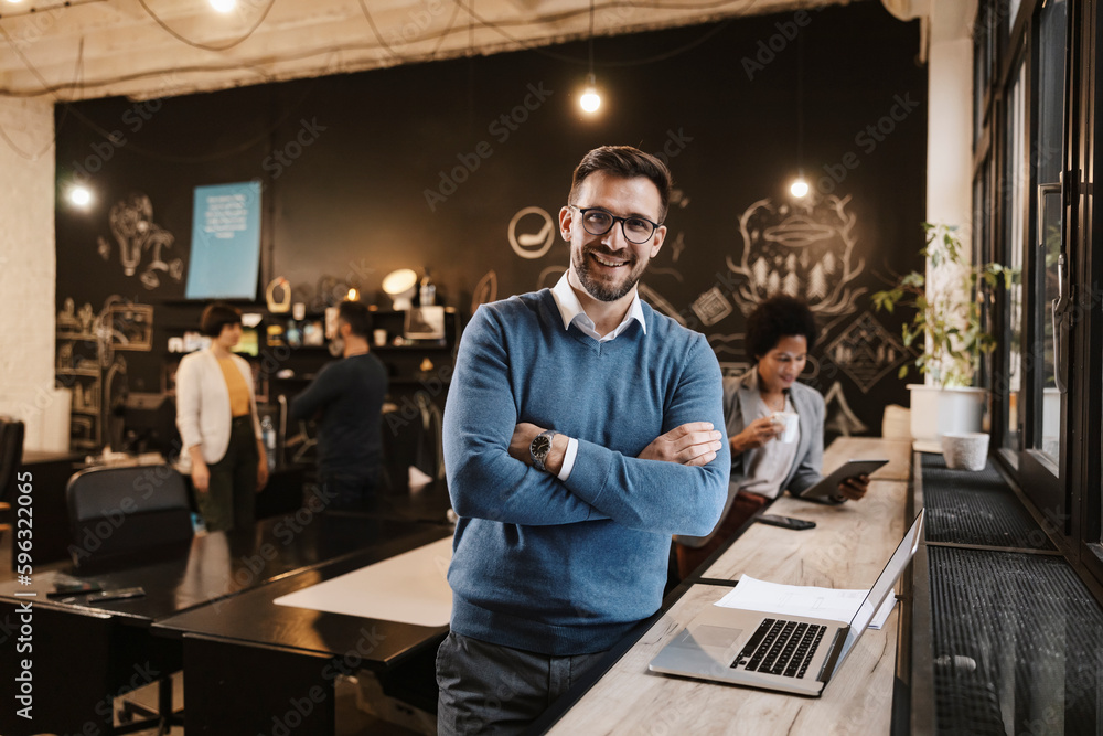 © Dusan Petkovic - Portrait of a successful businessman standing next to a laptop at cafe.