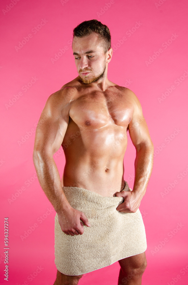 Fototapeta premium A young handsome guy washes in the shower. A man with a beautiful athletic body.