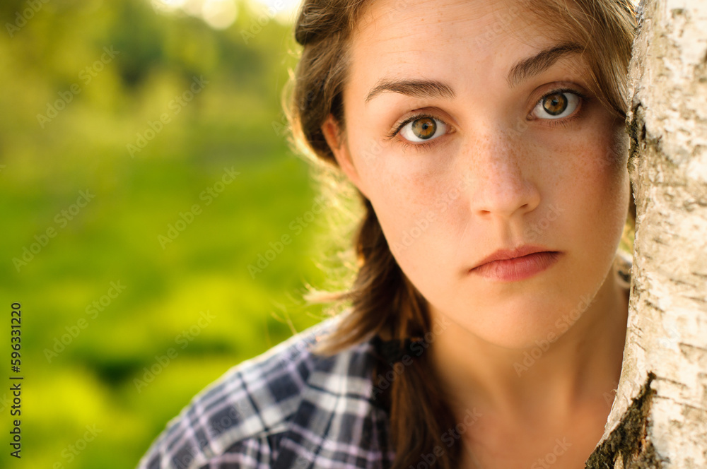 At peace with nature. Shot of a beautiful young woman leaning against a tree in a forest.