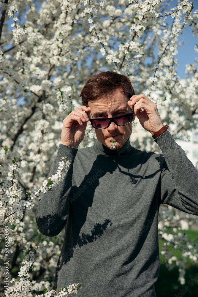 Man with flower in mouth looking at camera in blooming spring garden Man with flower in mouth looking at camera in blooming spring garden