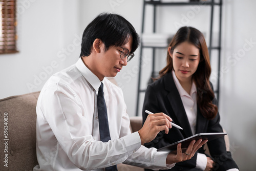 Young confident business people sitting at the office table working analyze on tablet and laptop computer with partner. Business concept