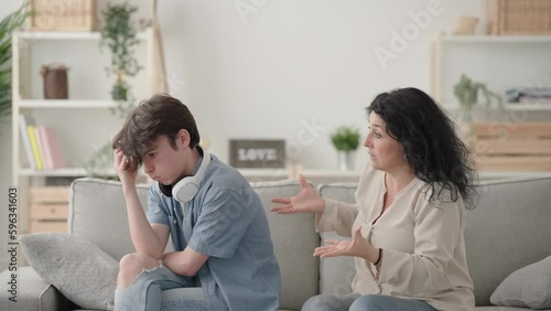 Mother trying to talk to teenager son, who is ignoring her. Frustrated woman scolding teenager boy