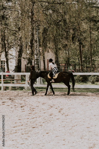 A woman instructor teaching girl how to ride a horse. Female rider practicing on a horseback learning equestrian sport. Active lifestyle and leisure activity concep