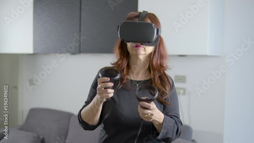 donna che usa visore di realtà virtuale in salotto photo