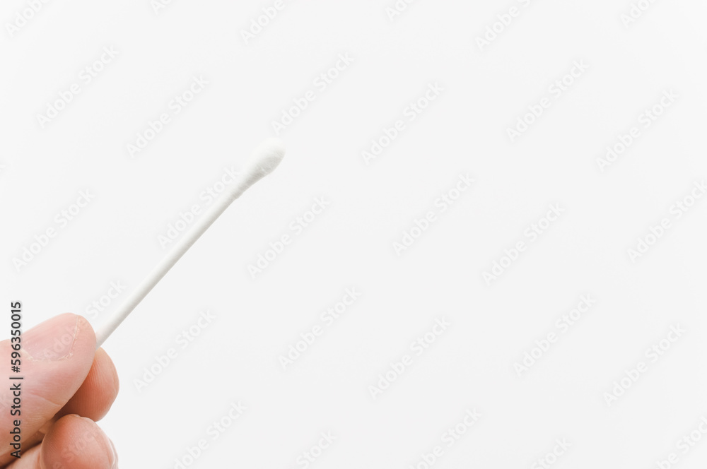 immagine con primo piano di dita che sorreggono un bastoncino in cotone ovattato su sfondo bianco immagine con primo piano di dita che sorreggono un bastoncino in cotone ovattato su sfondo bianco