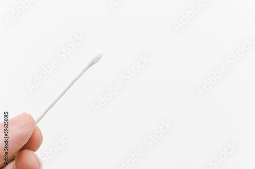 immagine con primo piano di dita che sorreggono un bastoncino in cotone ovattato su sfondo bianco photo