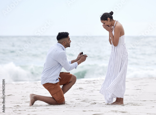 Will you marry me. Full length shot of a handsome young man proposing to his girlfriend on the beach.