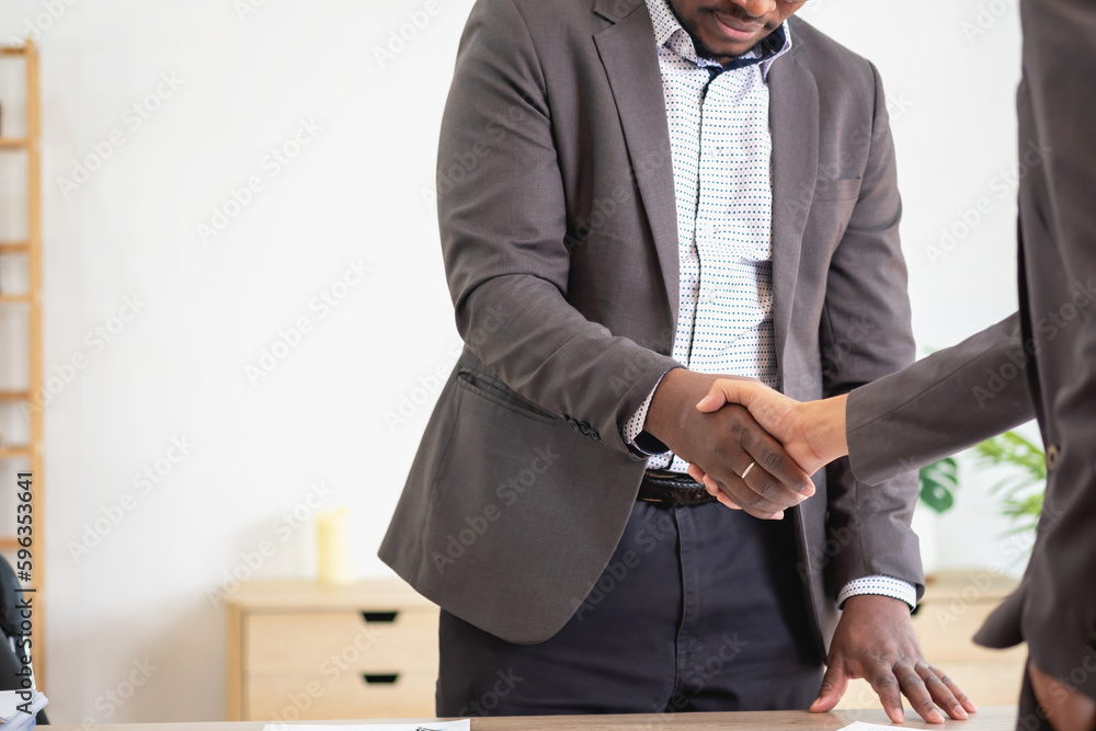 Satisfied black client shaking hands, thanking the manager for good financial deal African American businessmen shaking hands after successful business negotiations. Hiring. Buying services. Satisfied black client shaking hands, thanking the manager for good financial deal African American businessmen shaking hands after successful business negotiations. Hiring. Buying services.
