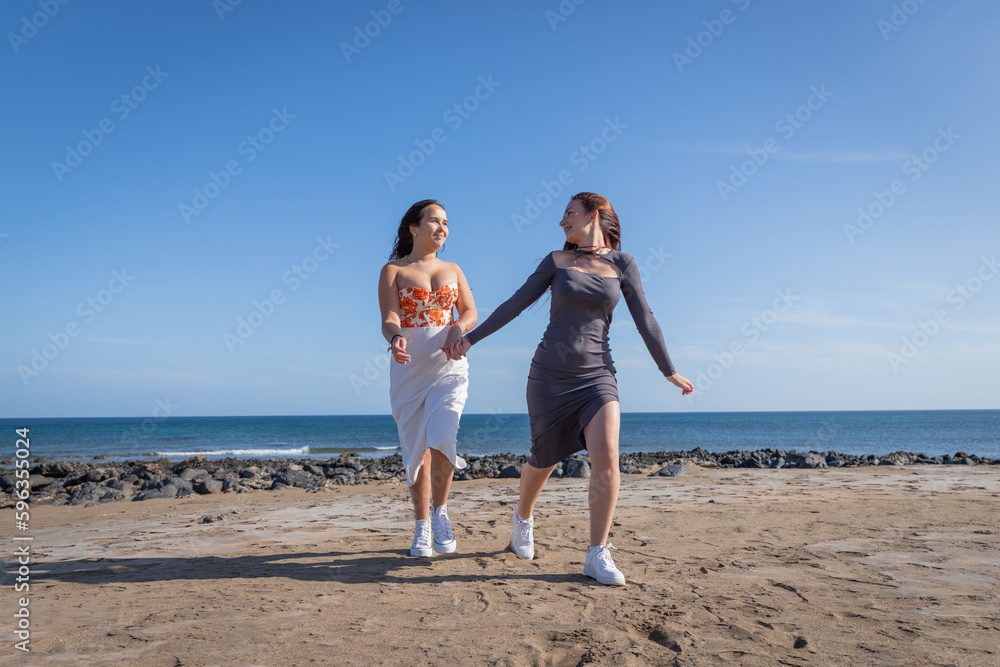 Two sisters hold hands and run at the beach, sister love Two sisters hold hands and run at the beach, sister love