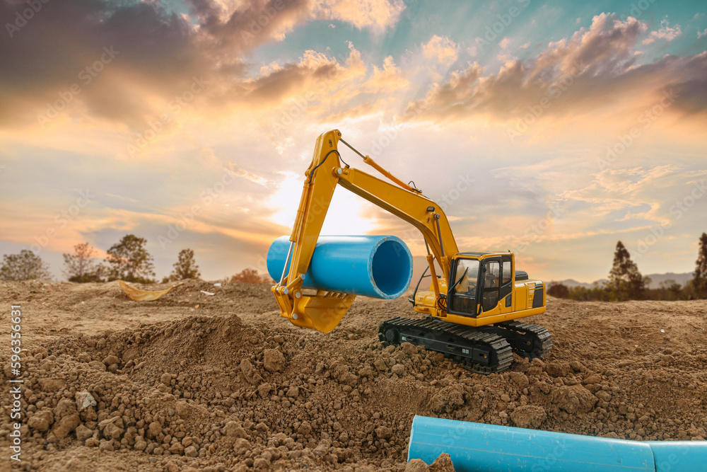 Crawler excavator is digging soil in the construction site and laying pipes with a sunset backgrounds. Crawler excavator is digging soil in the construction site and laying pipes with a sunset backgrounds.
