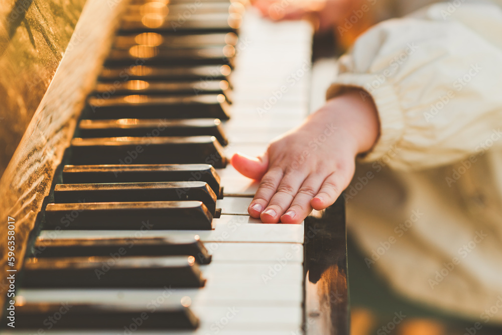 Close-up of hands of little girl playing piano. Selective focus.