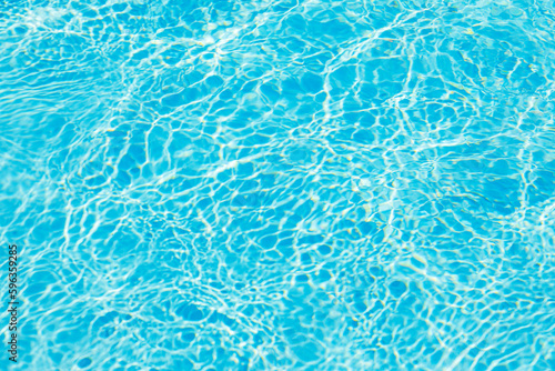 Blue pool water with sun reflections. Swimming pool water background