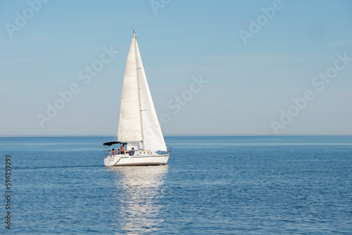 White sail boat on blue water of Lake Ontario. Sunny day, blue sky. Selective focus. Space for copy. Summer sports and activities, travel, freedom, adventure, journey concept.
