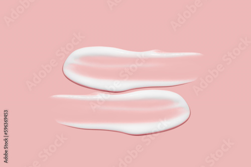 Lots of smears of cosmetic cream. Light, smooth surface. Texture of spreadable cream. Liquid creamy strokes. On a pink background. Cosmetic background, banner.