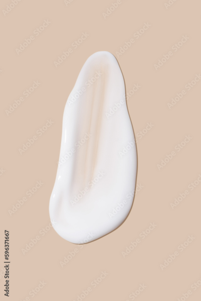 Fototapeta premium The flowing cream on a beige background. Smudged flowing smear of cosmetic cream.