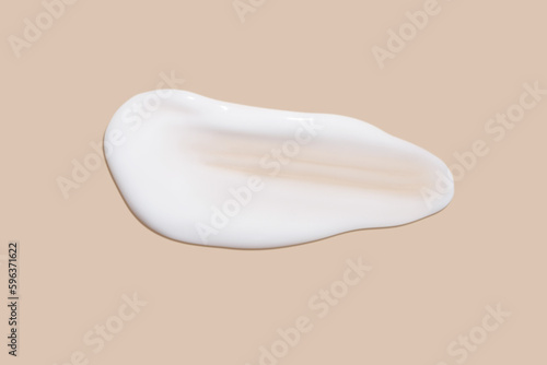 The flowing cream on a beige background. Smudged flowing smear of cosmetic cream.