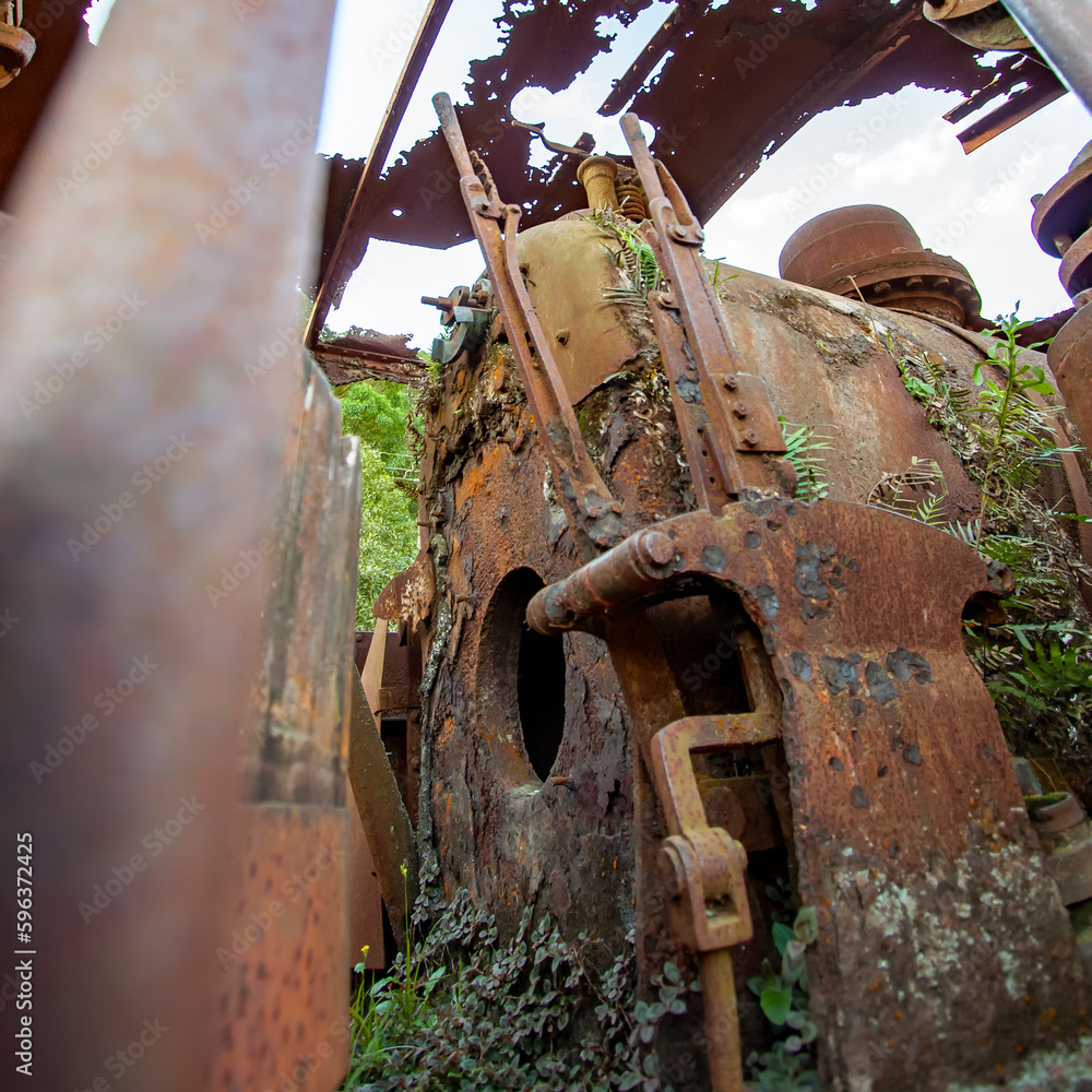 Ruínas de máquina de trem abandonado em cidade do Brasil. Ferrugem e natureza retomam cenário industrial pós apocalíptico