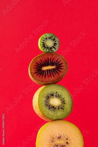 Still life with balancing kiwis of different varieties on a red. A balance of fruits, a modern and art concept.