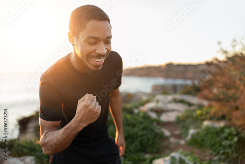 Smiling strong excited millennial african american man doing success and victory gesture with hand