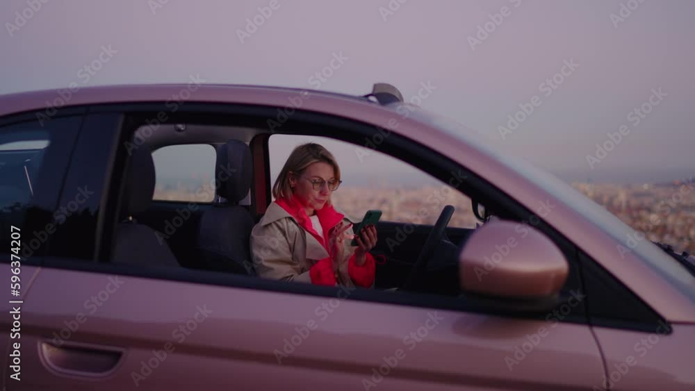 Content creator sitting in car, working on latest blogging post using trusty mobile phone application. Female blogger focused and dedicated to producing quality content for audience using smartphone Content creator sitting in car, working on latest blogging post using trusty mobile phone application. Female blogger focused and dedicated to producing quality content for audience using smartphone