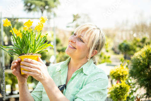 Die Mitarbeiterin einer Gärtnerei mit dem Topf mit Narzissen