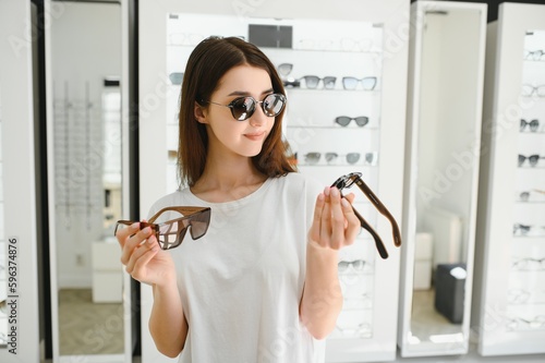 Cuadro en lienzo A young woman chooses on sunglasses in an optics store