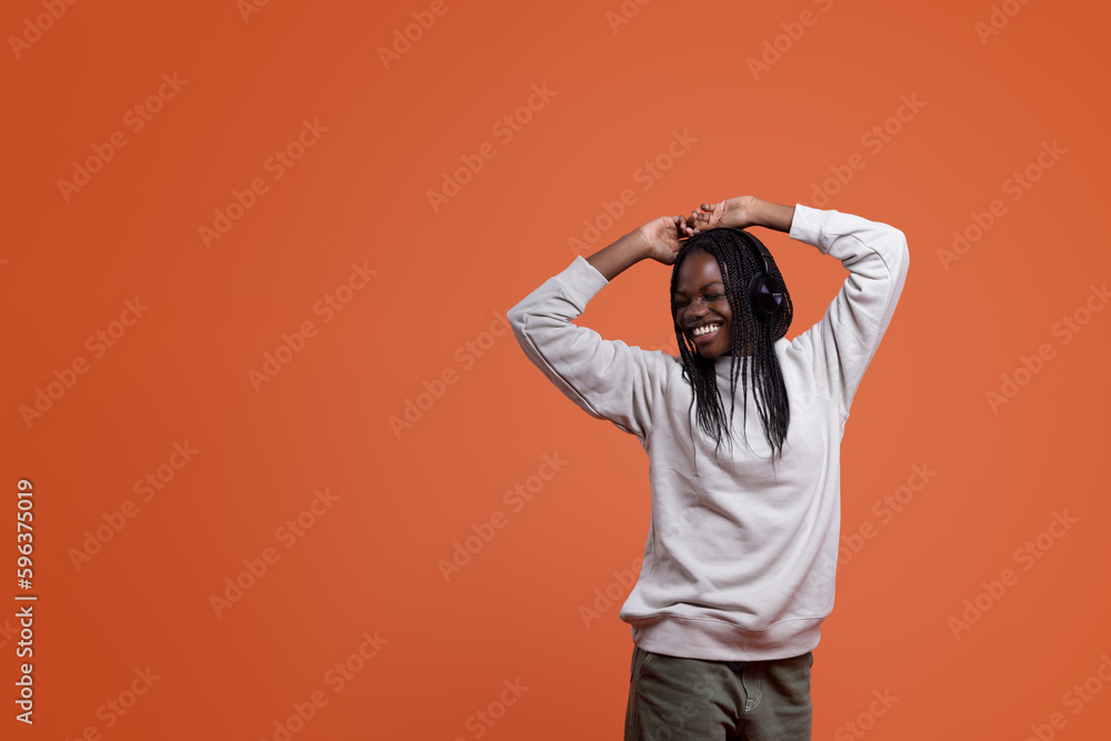 Happy black woman in headphones dancing with raised arms Happy black woman in headphones dancing with raised arms