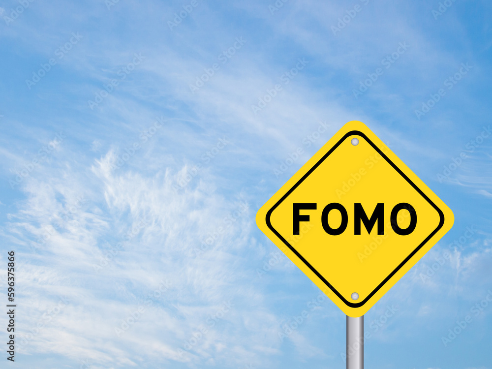 Fototapeta premium Yellow transportation sign with word FOMO (abbreviation of fear of missing out) on blue color sky background