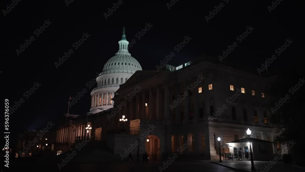 Moving camera showing the US Capitol with lights and flags waving in Washington DC at night set against a blue purple sky. Moving camera showing the US Capitol with lights and flags waving in Washington DC at night set against a blue purple sky.